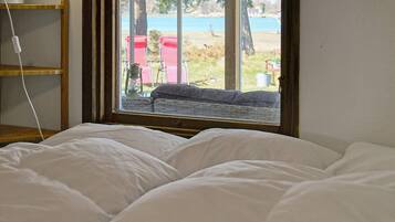 A bedroom with a bed, a window, and a view of outdoor furniture.