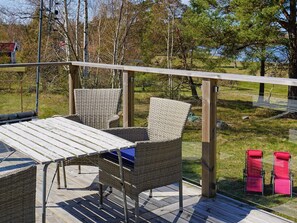 Een terras met rieten meubels, een tafel en twee rode stoelen.