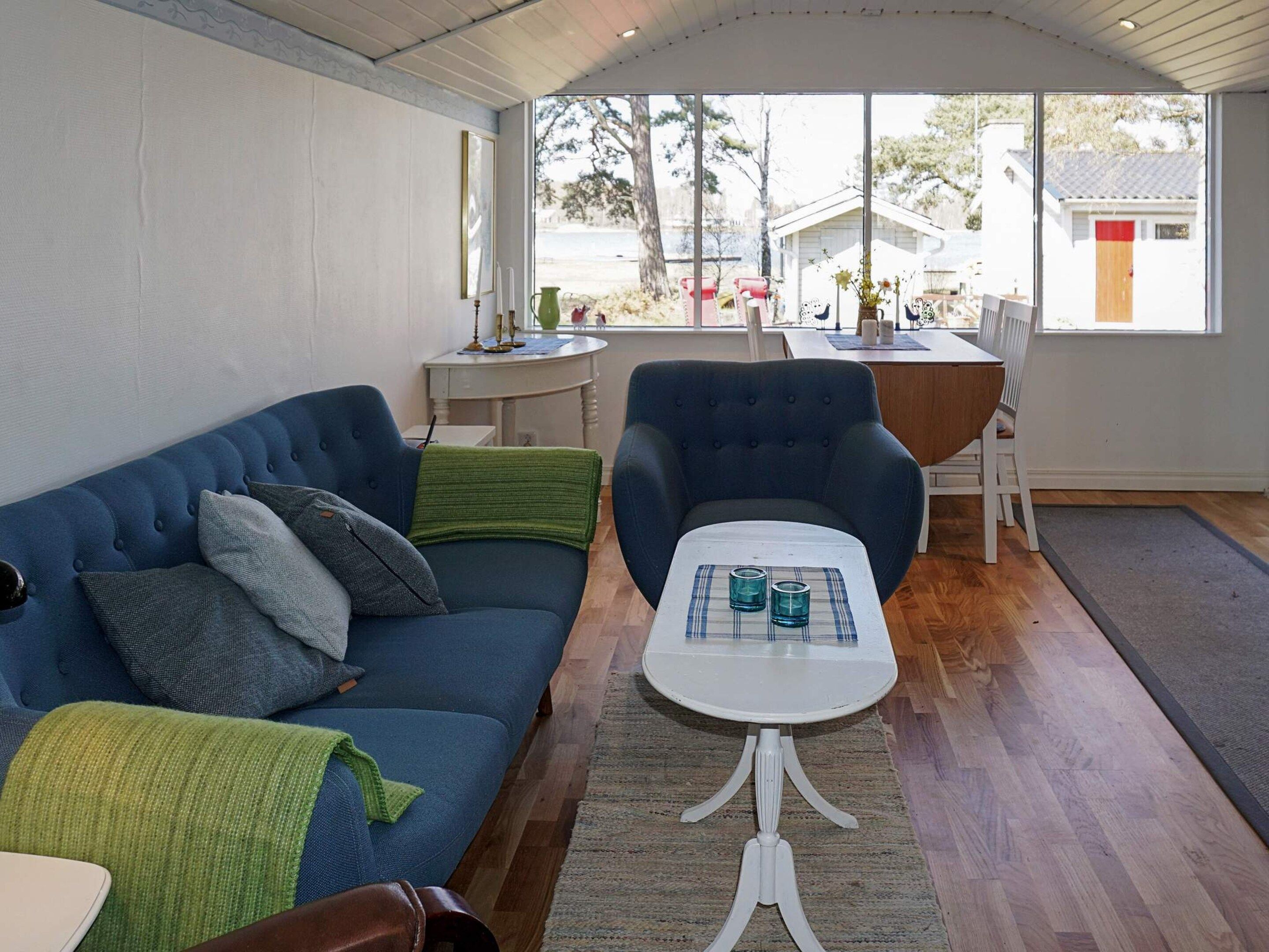 Un salon avec un canapé bleu, une table basse blanche et une vue sur l’extérieur.