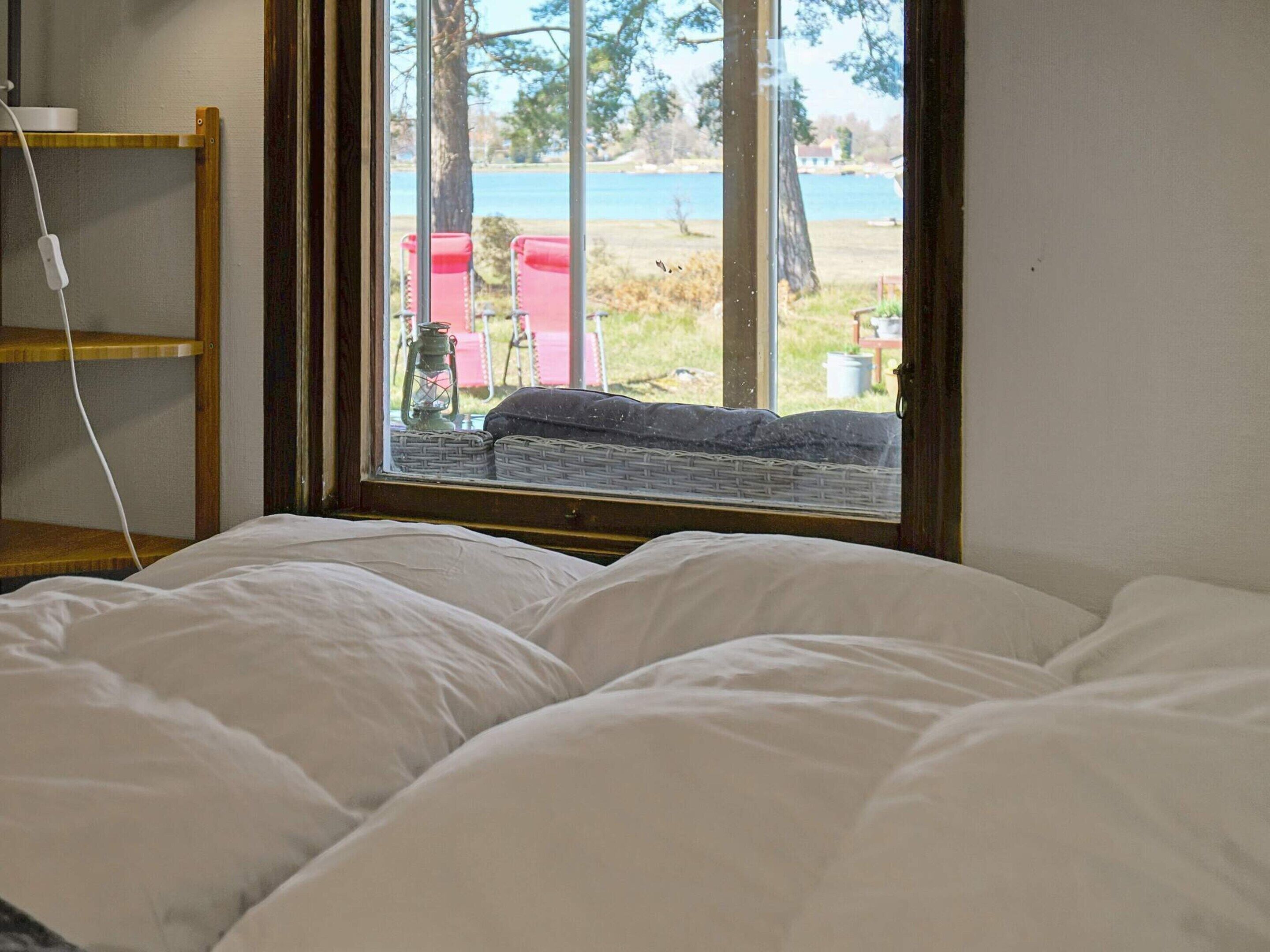 A bedroom with a bed, a window, and a view of outdoor furniture.