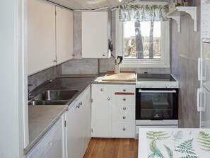 A compact kitchen with a sink, stove, and white cabinets. - 6 Person Holiday Home in Bergkvara (Bergkvara)