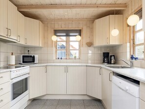 Une cuisine équipée de meubles en bois, d’un four à micro-ondes, d’une machine à café et d’un lave-vaisselle.