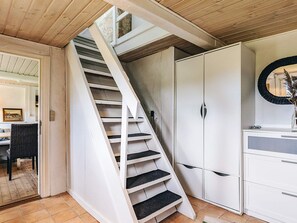 A staircase leading to a second floor, a white wardrobe, and a mirror on the wall.