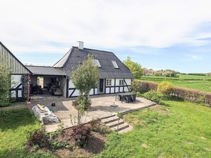 A traditional half-timbered house with a patio, outdoor seating, and a view of the surrounding countryside.