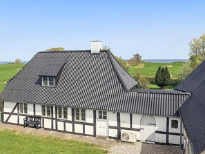 A traditional half-timbered house with a steep gabled roof, a chimney, and a small window.