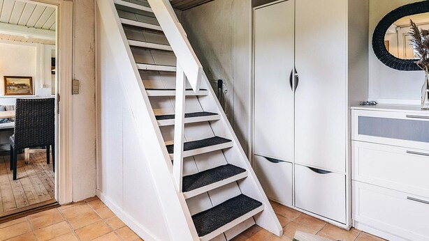 A staircase leading to a second floor, white cabinets, and a mirror on the wall. - 4 Person Holiday Home in Tranekaer (Tranekaer)