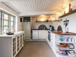 A compact kitchen with white cabinetry, a wooden countertop, and a built-in oven.