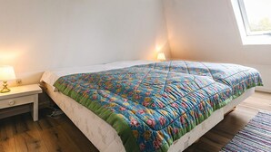 A bedroom with a bed, a nightstand, a lamp, and a window. - 4 Person Holiday Home in Tranekaer (Tranekaer)