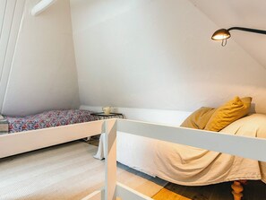 Ein kleines, gemütliches Schlafzimmer mit einem Etagenbett, einem Nachttisch mit Lampe und einer schlichten weißen Wand.