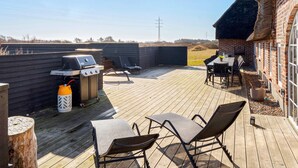 Una terraza exterior con una parrilla, sillas de lounge y una mesa.