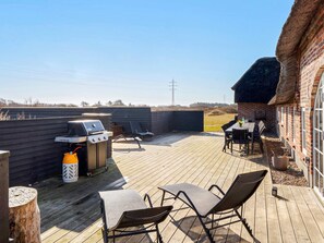 An outdoor deck with a barbecue grill, lounge chairs, and a table.