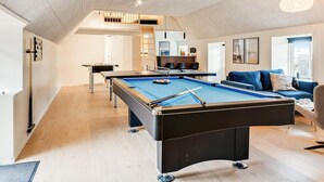 Una sala de estar moderna con una mesa de billar, un sofá y un comedor.