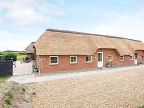 A thatched-roof building with a gravel driveway and outdoor seating area.