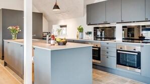 Una cocina moderna con armarios grises, una isla central y electrodomésticos de acero inoxidable.
