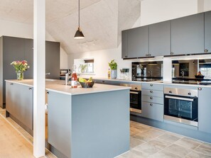 A modern kitchen with grey cabinetry, a central island, and stainless steel appliances.