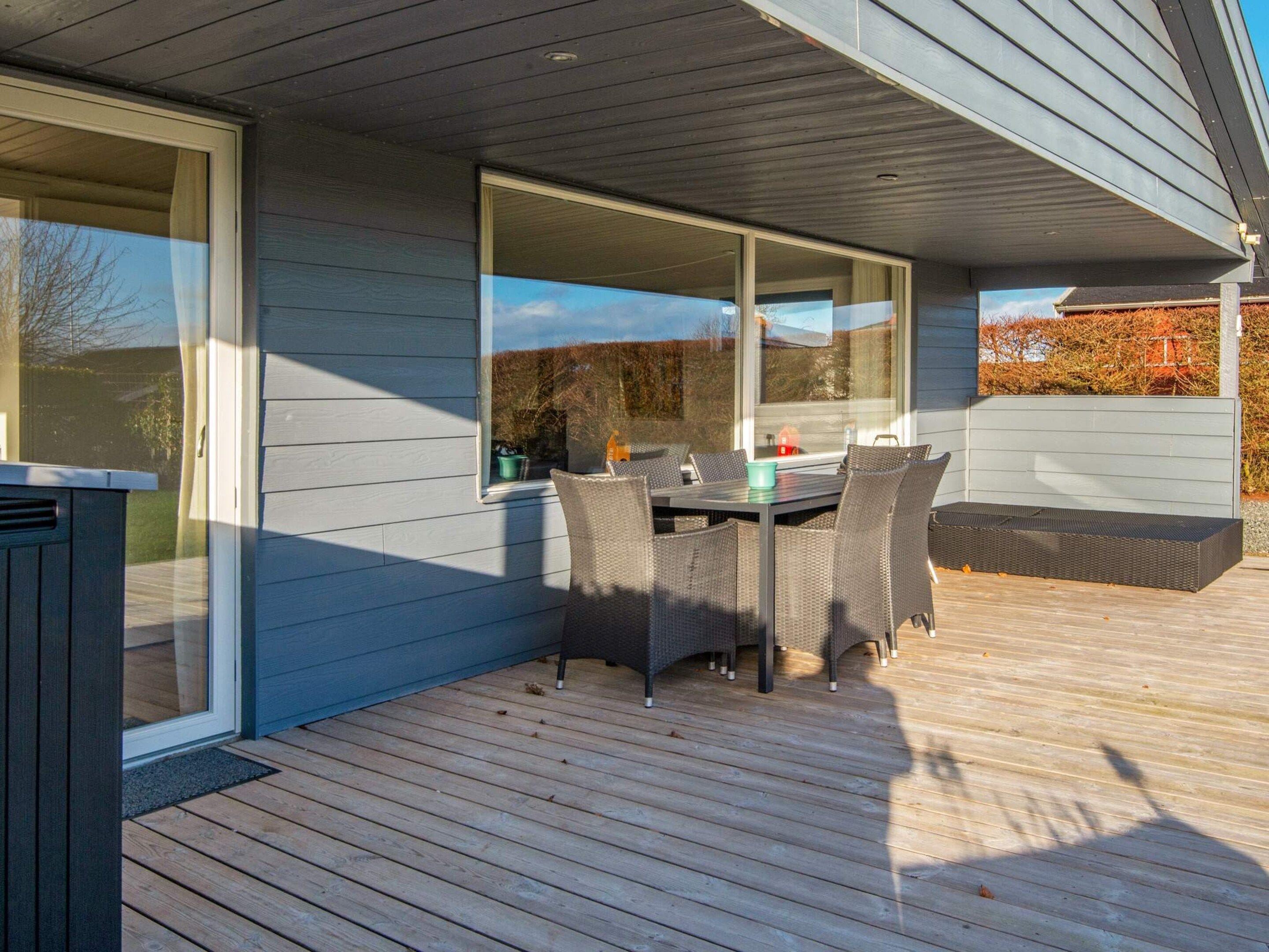 A deck with a table and chairs, a sliding glass door, and a view of the outdoors.