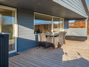 A deck with a table and chairs, a sliding glass door, and a view of the outdoors.