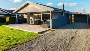 A modern house with a covered patio, a barbecue area, and a gravel driveway. - 4 Star Holiday Home in Hejls (Hejls)