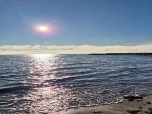 En strand med en brygga som sträcker sig ut i vattnet, under en klar himmel.