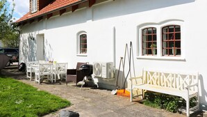 A white building with a red-tiled roof, a white bench, and outdoor furniture. - 8 Person Holiday Home in Storvorde (Storvorde)