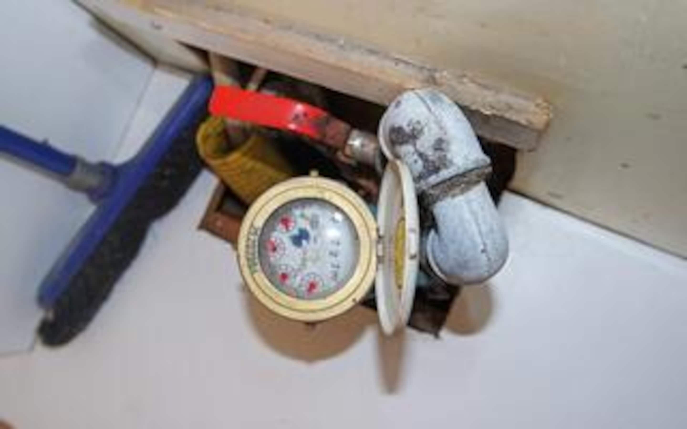 A toilet with a visible tank, a blue pipe, and a red pipe.