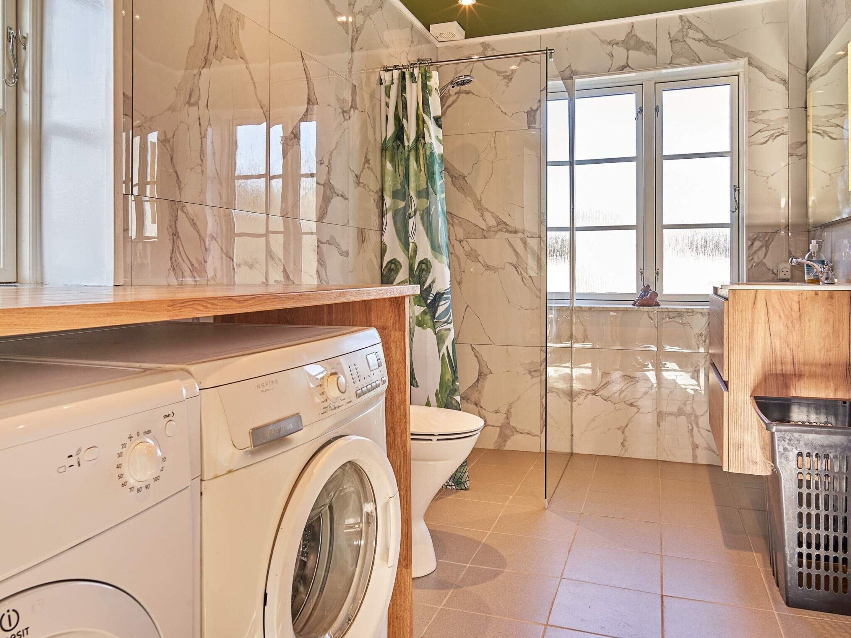 Ein kleines Badezimmer mit Waschmaschine, Toilette und Duschbereich.