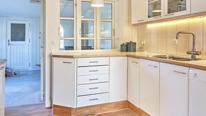 A kitchen with white cabinets, a wooden countertop, a built-in sink, and a window above the sink. - 4 Person Holiday Home in Nexo (Nexø)