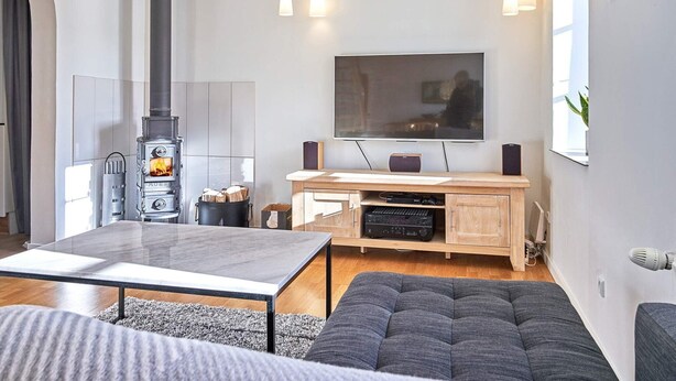 A modern living room with a fireplace, a flat-screen TV, wooden furniture, and a cozy seating area. - 4 Person Holiday Home in Nexo (Nexø)