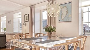 A dining area with a table set for six, wooden chairs, a chandelier, a map on the wall, and a plant on the table. - 4 Person Holiday Home in Nexo (Nexø)