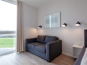 A modern living room with a grey sofa, a framed artwork, and three wall-mounted lamps.