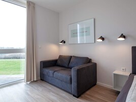 Una sala de estar moderna con un sofá gris, una obra de arte enmarcada y tres lámparas fijadas a la pared.