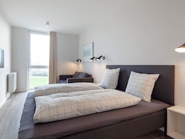 Una habitación de hotel moderna con una cama grande, un sofá y vistas al exterior.