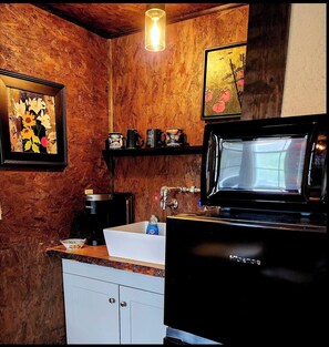 Bathroom features a sink, coffee maker, and shelf with artwork above.