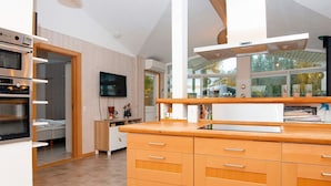 A modern kitchen with built-in appliances, a large window, and a view of the outdoors.