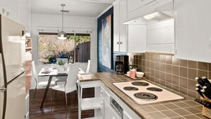 Una cocina moderna con armarios blancos, una zona de comedor con mesa y sillas, y vistas al exterior.