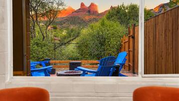 Un patio con sillas azules y una mesa, con vistas a un paisaje montañoso.