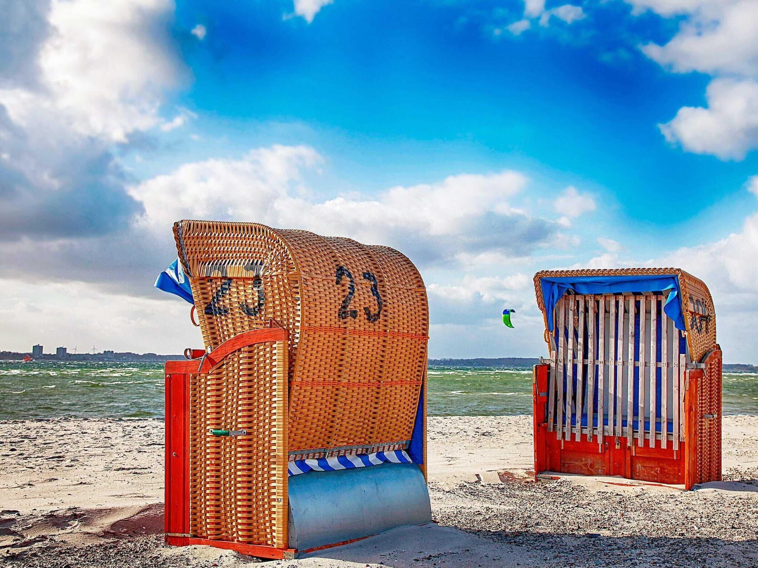 Deux cabanes de plage, numérotées 23 et 24, une plage de sable et une vue sur la mer.