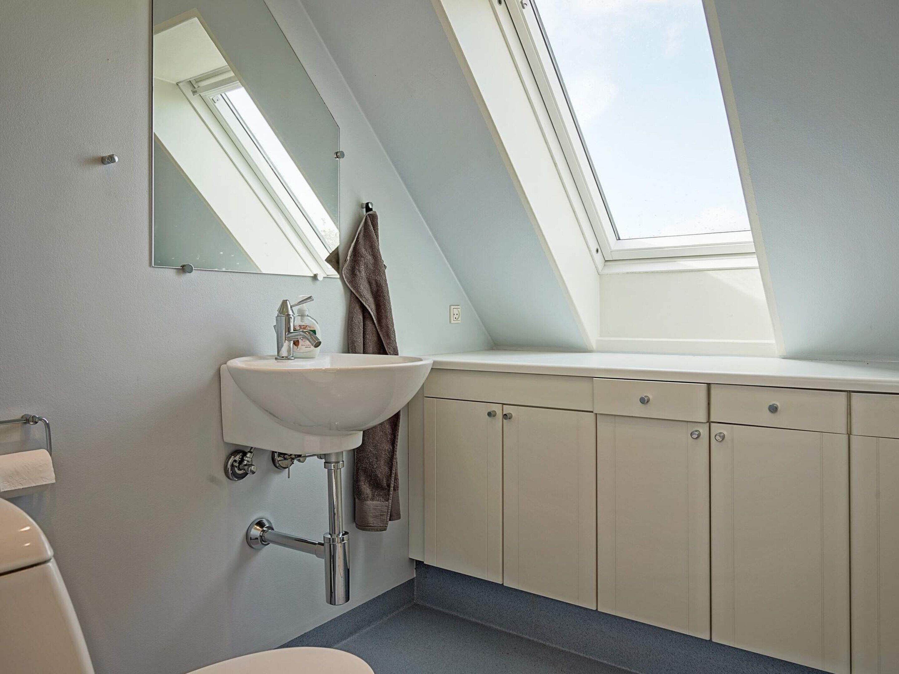 A bathroom with a skylight, a sink, and cabinets.