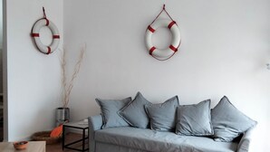 A living room with a grey sofa, two life rings on the wall, a small table with a bowl, and a potted plant. -  M335 - Marcelli, large two-room apartment with sea view with balcony (Marcelli)