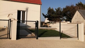 A building with a red roof, a gated entrance, and a dirt ground.
