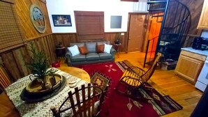 Uma sala de estar acolhedora com um sofá, cadeiras de madeira, uma mesa de centro e um tapete vermelho.