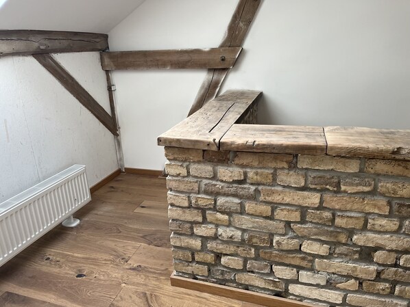Esquina de una habitación con pared de piedra, vigas de madera y un radiador blanco.