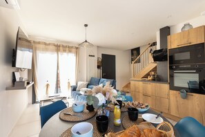 Een moderne woonkamer met een bank, salontafel en een keukenhoek met een magnetron en oven.