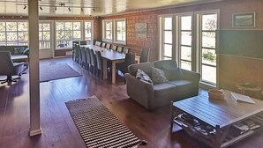 A spacious room with a large dining table, several chairs, a sofa, and a coffee table.