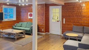 A cozy cabin interior with wooden walls, a green sofa, a gray sofa, and a wooden coffee table.