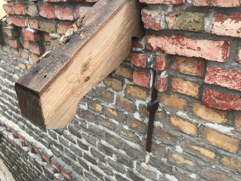 Una viga de madera adosada a un muro de ladrillo.