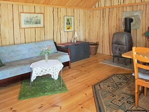 Une pièce chaleureuse avec un décor intérieur en bois, un canapé, une petite table avec un vase, une cheminée et un tapis.