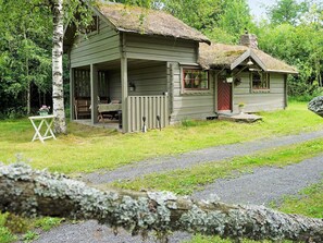 A rustic cabin with a porch, a small attached shed, and a thatched roof. - 5 Person Holiday Home in Tingsryd (Tingsryd)