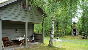 A rustic wooden cabin with a porch, two tables, and chairs. - 5 Person Holiday Home in Tingsryd (Tingsryd)