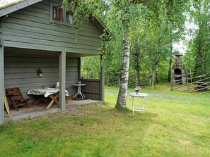 A rustic wooden cabin with a porch, two tables, and chairs. - 5 Person Holiday Home in Tingsryd (Tingsryd)